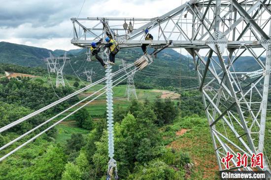 6月18日，工人在安装输电线路绝缘子串。（无人机照片）中新社记者 瞿宏伦 摄