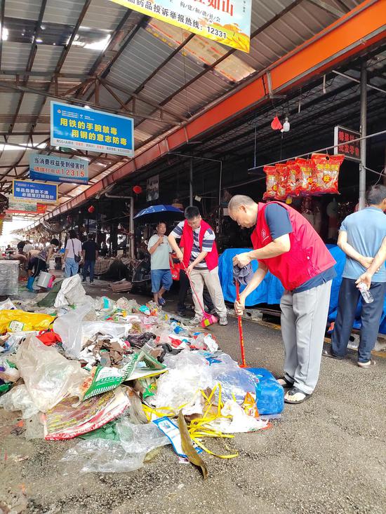 图为帮扶队伍帮助清扫垃圾现场照片。李群摄
