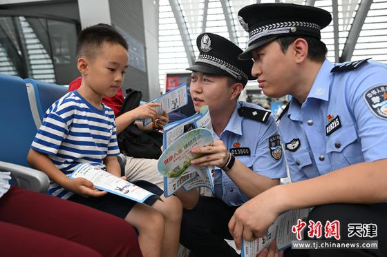 图为天津铁路公安处民警向正在候车的小朋友宣传法律常识。（北京铁路公安局天津铁路公安处供图）