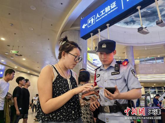 图为天津铁路公安处天津站派出所民警在执勤中帮助旅客解答疑问（北京铁路公安局天津铁路公安处供图）