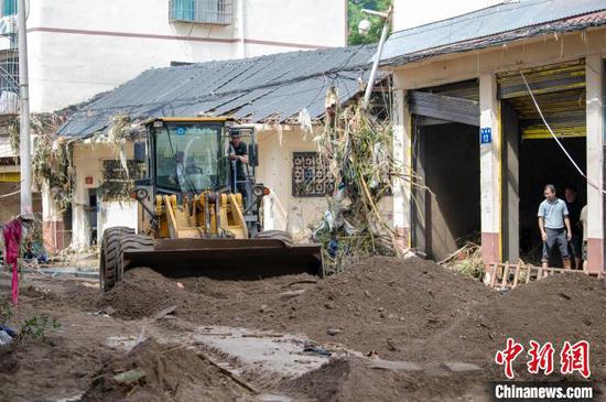 6月25日，从江县城区，工作人员驾驶铲车清理街道淤泥。吴德军 摄