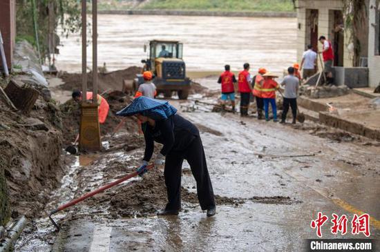 6月25日，随着都柳江水位平稳下降，贵州省黔东南苗族侗族自治州从江县积极开展清淤消杀工作，帮助民众恢复正常的生活和生产。图为在从江县城区，党员和干部群众齐力清理街道淤泥。吴德军 摄