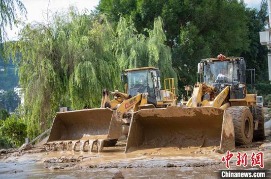 6月25日，从江县城区，工作人员驾驶铲车清理街道淤泥。吴德军 摄