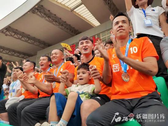 新疆岳普湖足球队阿卜杜乃比·乌布力(右一)、热合曼·乌布力(右三)、艾海提·斯迪克(左三)、凯赛尔·塔依尔(左二)等队员代表现场为“喀什杯”参赛健儿加油。石榴云/新疆日报记者 董亮摄