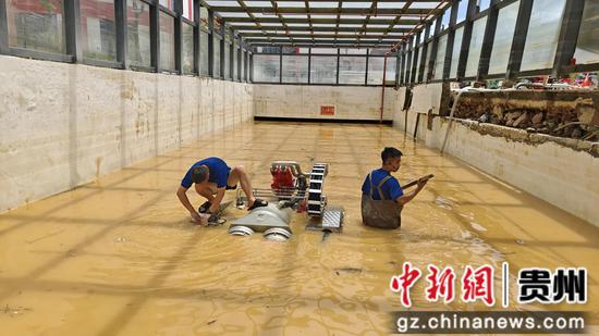 图为贵阳市消防救援支队特勤二站黎中豪正在齐腰的水中安装调试排水设备