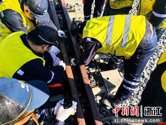 图为:工人们检测钢轨。中新社发 贺瑞明 摄