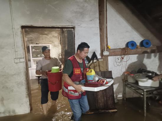 图为柳州烟草驻同乐村工作队员韦宇雄帮助受灾村民转移生活物资。兰曲妮 摄 图为柳州烟草驻同乐村工作队员韦宇雄帮助受灾村民转移生活物资。兰曲妮 摄