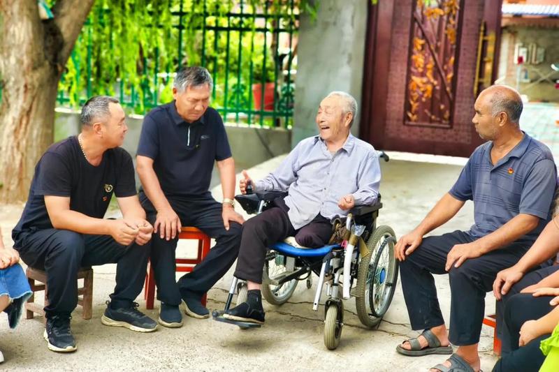 图为焦应锡老人（坐轮椅者）与人交谈。