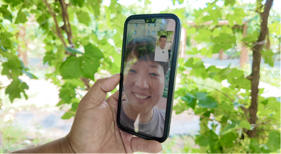 远在河南的王女士在视频连线里看到自己认养的葡萄硕果累累,高兴得合不拢嘴。哈斯业提古丽 摄。