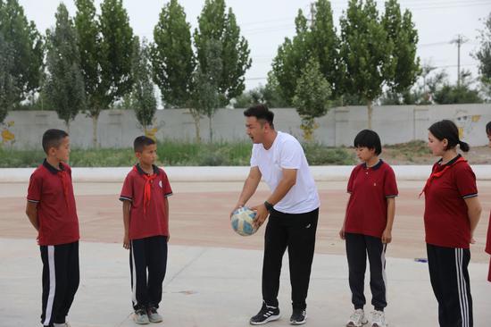 岳普湖县第三小学体育老师正在操场上认真地教学生们踢足球的各项技巧。(陈冰清 摄)