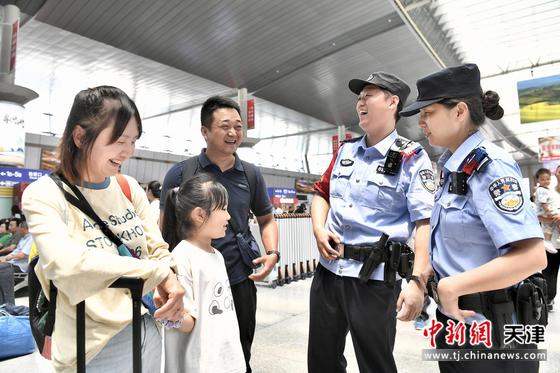 北京铁路公安局天津公安处执勤民警与旅客开心交谈，帮助旅客解决困难。（北京铁路公安局天津公安处供图）