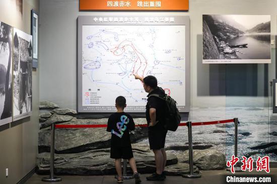 7月16日，一位家长在给孩子讲解“中央红军四渡赤水河、南渡乌江要图”。暑假期间，位于贵州省遵义市红花岗区的遵义会议纪念馆游客络绎不绝。中新社记者 瞿宏伦 摄