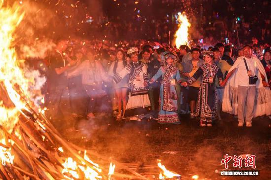 图为当地民众和各地游客围着篝火跳舞。中新社记者 瞿宏伦 摄 图为当地民众和各地游客围着篝火跳舞。中新社记者 瞿宏伦 摄