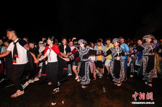 图为当地民众和各地游客围着篝火跳舞。中新社记者 瞿宏伦 摄 图为当地民众和各地游客围着篝火跳舞。中新社记者 瞿宏伦 摄