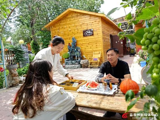 山坡村的不二凡庭民宿,游客在葡萄藤下喝茶。记者王薇 摄