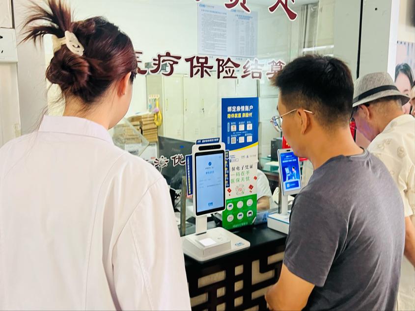 上图为：7月15日，在昌吉市建国路社区卫生服务中心，参保群众通过“刷脸付”结算费用。记者左晓雨 摄