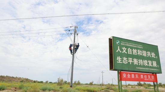 新疆远航电力工程有限公司的工作人员各司其职,有的在杆塔上固定导线,有的在地面整理线缆,有条不紊推进一棵树管护站新建10千伏架空线路施工。
