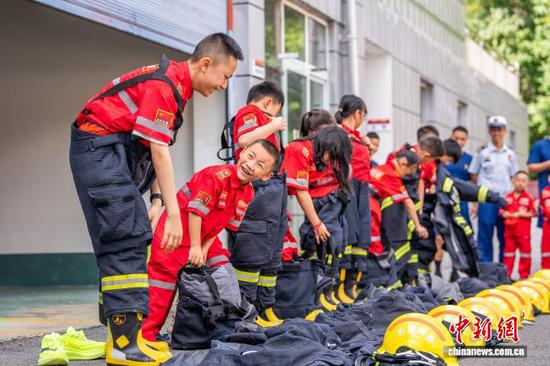 7月28日,在贵州省毕节市七星关区南环路消防救援站,孩子们正在体验穿戴灭火防护服。罗大富 摄 7月28日,在贵州省毕节市七星关区南环路消防救援站,孩子们正在体验穿戴灭火防护服。罗大富 摄