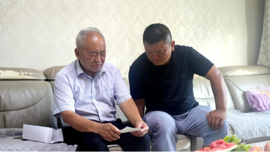 田宝远给儿子田青泉分享年轻时参加柯柯牙荒漠绿化工程的故事。赵新昌 摄