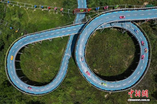 7月31日，游客在体验滑板车。进入暑期以来，位于贵州省黔西市中建苗族彝族乡的羊驼小镇景区旅游火热，吸引各地游客前来游玩、避暑、纳凉。（无人机照片）中新社记者 瞿宏伦 摄