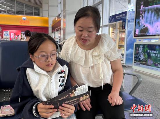 图为8月4日，张娅与妈妈在机场候机大厅看机票信息。中新网记者袁超 摄