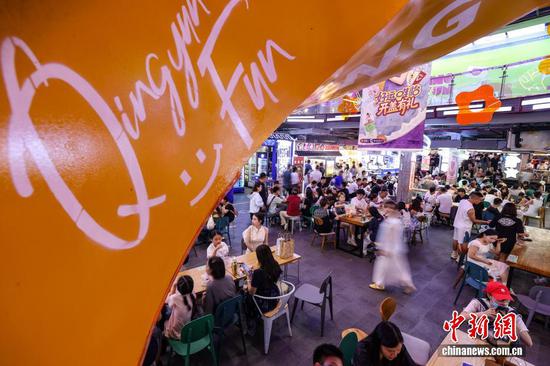 图为游客在青云市集选购、品尝当地小吃。