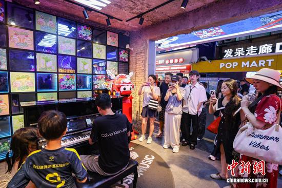 图为一名游客在青云市集弹共享钢琴被围观。