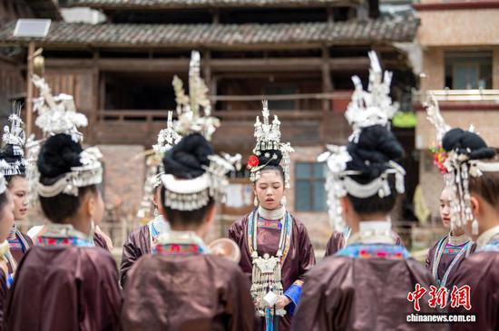 2025年8月7日是贵州省黔东南苗族侗族自治州从江县西山镇顶洞村一年一度新米节，也是当地侗族的成人礼。全村即将迈入成人行列的少男少女，身着节日盛装，欢聚于鼓楼与风雨桥之间，吟唱着悠扬的侗歌，向先祖虔诚地宣告自己的成年，期盼着在爱情的田野上自由驰骋，在事业的征途上勇敢前行，祈福得到先祖的保佑。图为顶洞村的侗族少男少女前往鼓楼准备参加成人礼。（无人机照片）吴德军 摄