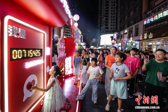 图为游客在青云市集排队体验打卡设备。