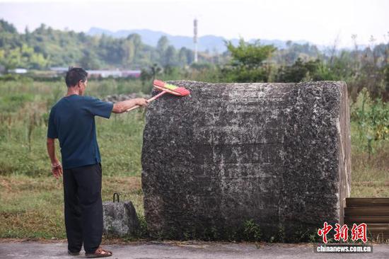 8月10日，工作人员刘荣雨在清扫黄平旧州机场修建时期留存的大石碾。中新社记者 瞿宏伦 摄