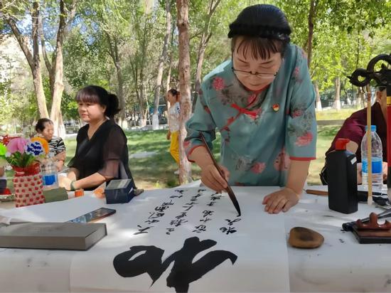 在阜康市纪委监委联合博峰社区开展的廉政教育活动中，书法爱好者正在挥毫创作。王筱庆摄0