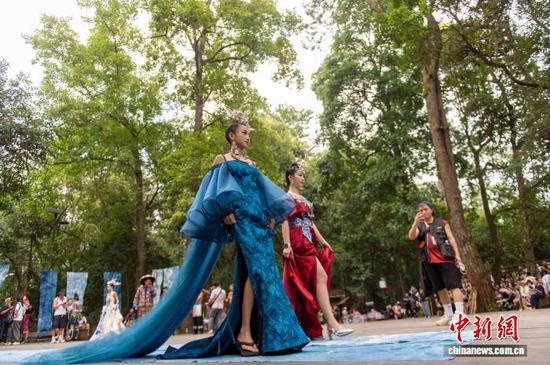 2025年8月9日，贵州省黔东南苗族侗族自治州从江县岜沙苗寨，平日用于庆典、表演的芦笙堂被临时改造成秀场，为游客带来一场时尚的“村T”秀。图为模特在岜沙苗寨走秀。吴德军 摄