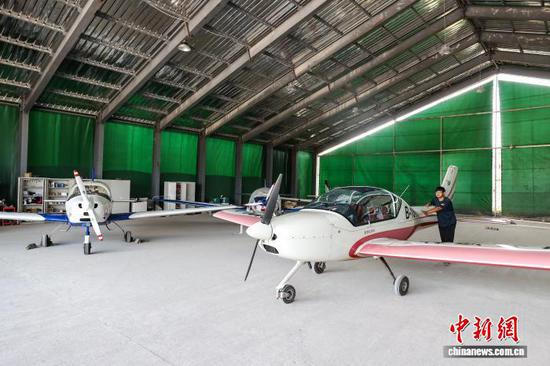 8月10日，机务人员刘家旭将航空器从黄平旧州机场机库推出。中新社记者 瞿宏伦 摄