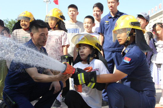 图为学生体验消防水枪。