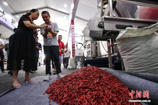 图为参观者在了解一款辣椒烘干设备。中新社记者 瞿宏伦 摄