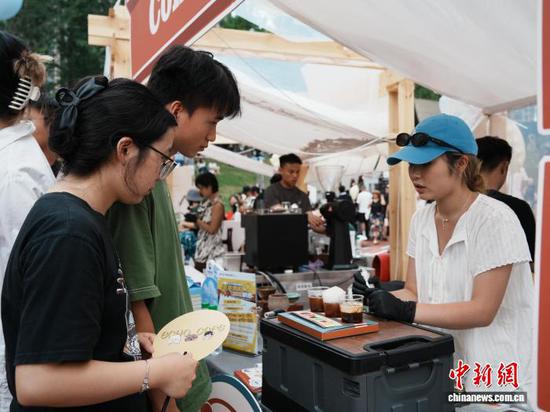 8月17日，贵州省贵阳市观山湖区，咖啡师在咖啡集市上为游客介绍咖啡产品。中新社记者 周燕玲 摄