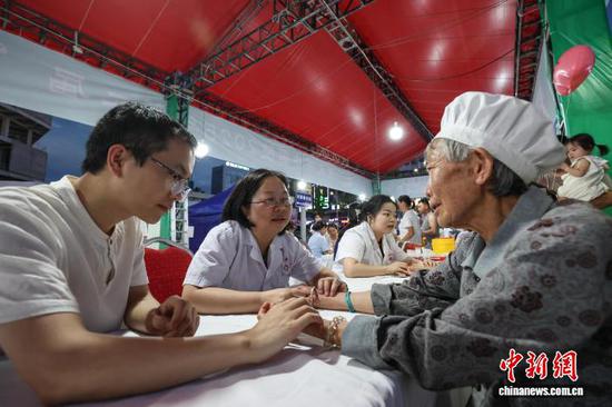 图为医护人员为市民把脉问诊。中新社记者 瞿宏伦 摄
