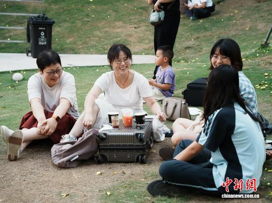 8月17日，贵州省贵阳市观山湖区，游客在咖啡集市旁的草坪上喝咖啡聊天。中新社记者 周燕玲 摄