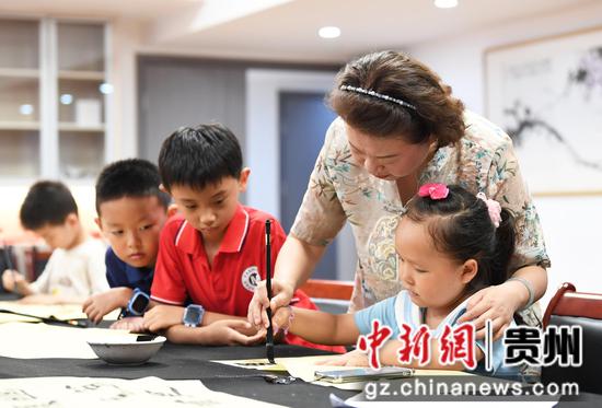 8月18日，在贵阳市南明区文化馆暑期未成年人文艺培训班，书法老师正在指导小朋友们学习书法。