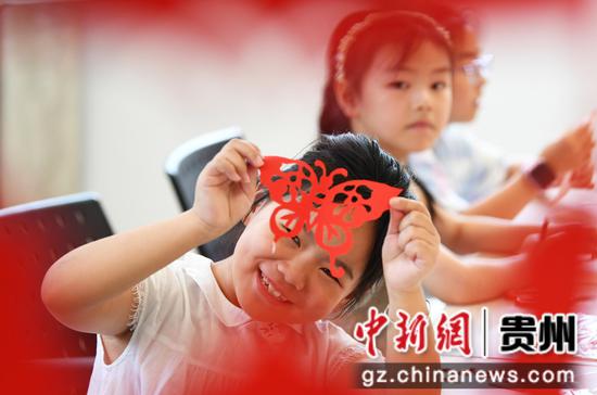 8月18日，在贵阳市南明区文化馆暑期未成年人文艺培训班，一名小朋友正展示自己的剪纸作品。