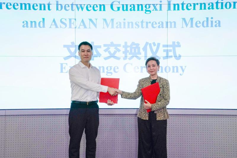 广西日报社副总编辑宋春风与泰国大众传播机构副总裁瓦查琳交换合作文本。
