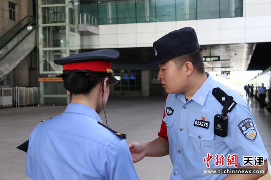 图为北京铁路公安局天津公安处乘警支队民警韩士龙在值乘前与列车工作人员沟通交流，研究相关工作。（北京铁路公安局天津公安处供图）