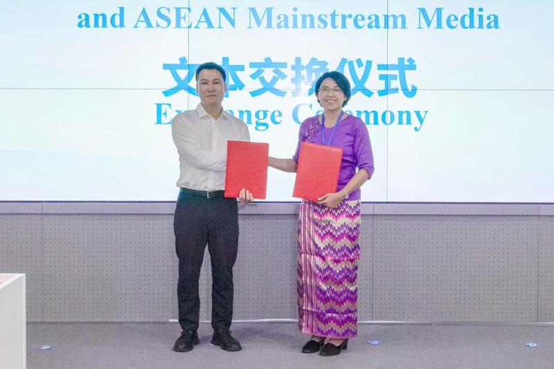 广西日报社副总编辑宋春风与缅甸未来新闻社副社长苏米亚交换合作文本。