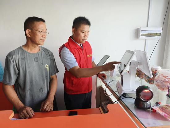 图为宜州烟草志愿者指导旅游终端户操作云POS系统。潘英 摄