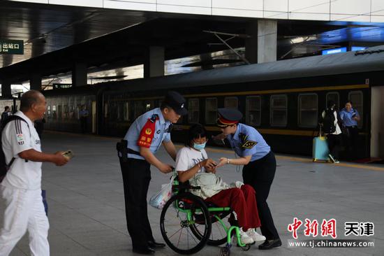 图为北京铁路公安局天津公安处乘警支队民警韩士龙帮助身患疾病旅客上车，做好爱心服务工作。（北京铁路公安局天津公安处供图）