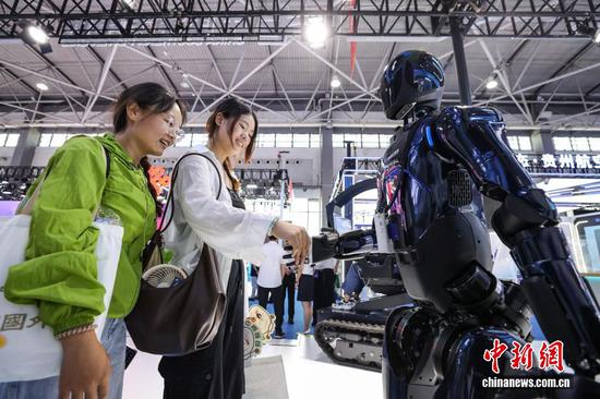 8月28日，以“数聚产业动能智启发展新篇”为主题的2025中国国际大数据产业博览会在贵州省贵阳市开幕。图为参观者在中国南方电网展区和大瓦特人形机器人握手互动。