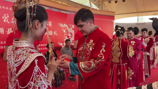 在婚礼现场,男士正专注地给女士戴戒指,二人共同沉浸在这庄重又甜蜜的时刻。