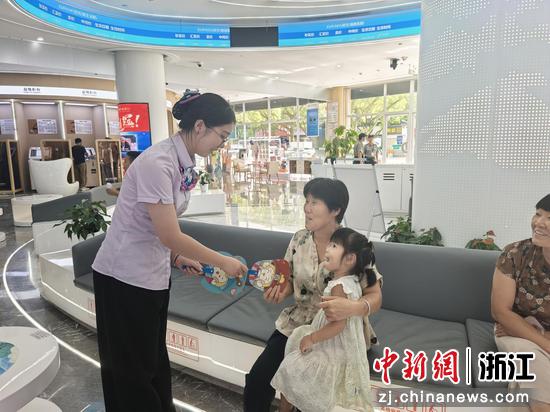 农行工作人员发放印有信用标语的小折扇。 农行温州分行 供图 农行工作人员发放印有信用标语的小折扇。 农行温州分行 供图