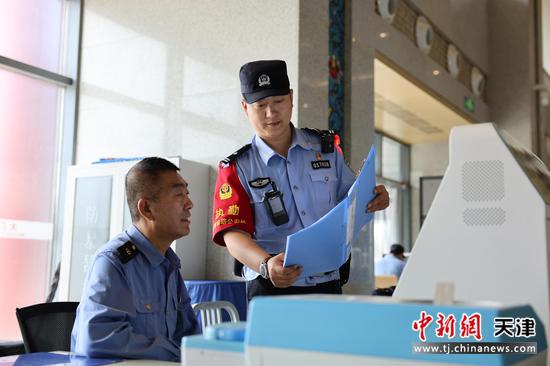 图为北京铁路公安局天津公安处民警在安检点与车站工作人员交流。（北京铁路公安局天津公安处供图）