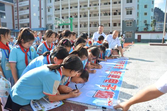 图为学生们在“守护成长,拒绝电子烟”横幅上签字。 吴俊鹏 摄